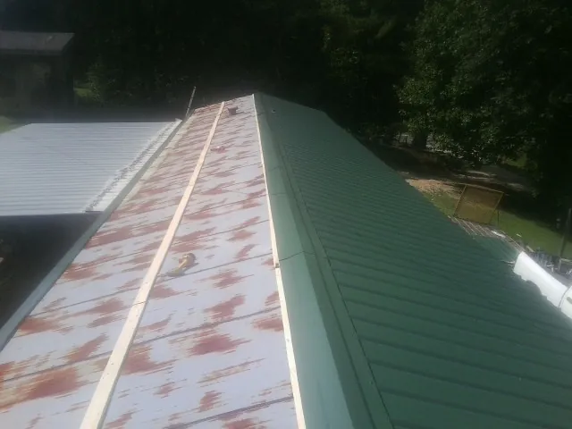 Old rusted panels beside newly installed green metal roofing — Wind Damage Roof Repair by Roofing Brothers in Cumberland City