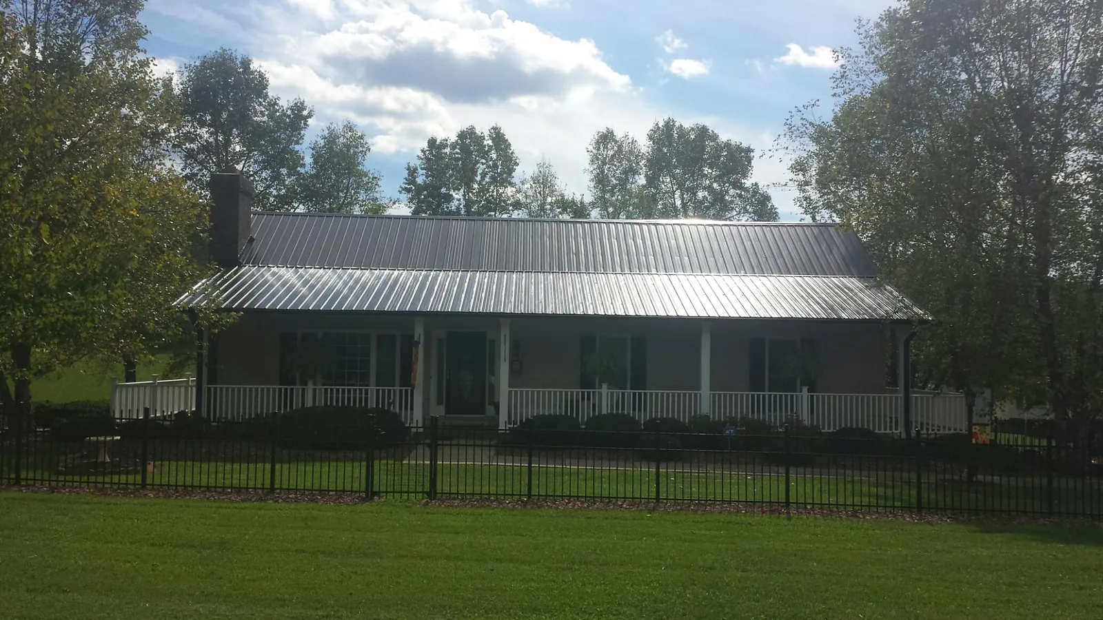 Gray metal roof on a brick ranch with a full width front porch — Gutter Guard Installation work by our crew in Cumberland City