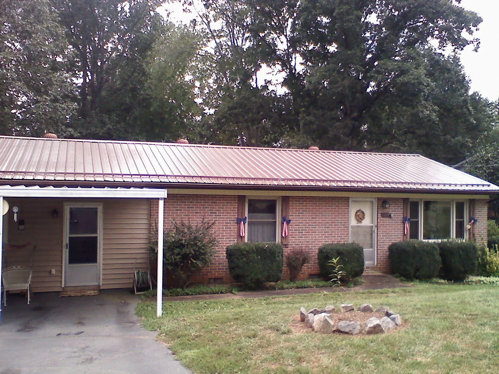 Bronze metal roof and carport on a brick ranch home — Roof Repair work by our crew in Cumberland City