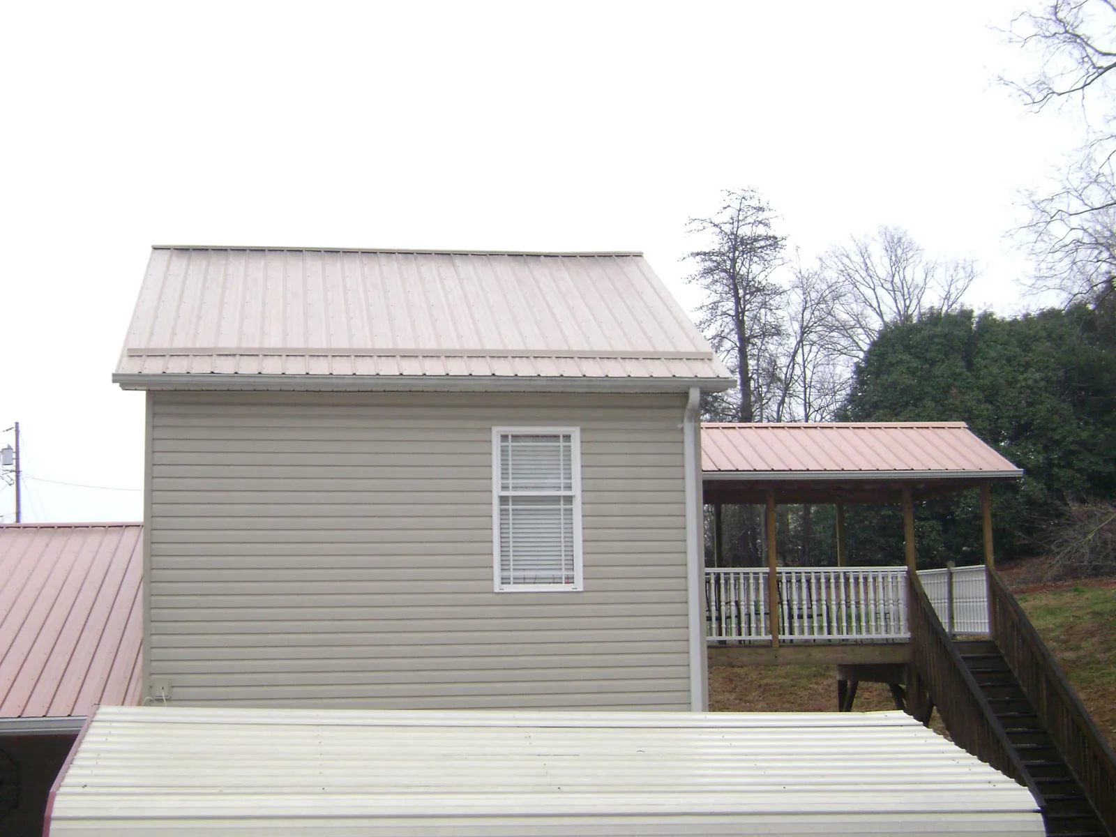 Tan metal roofs on a two story addition and attached porch, from a Roof Replacement job in Cumberland City