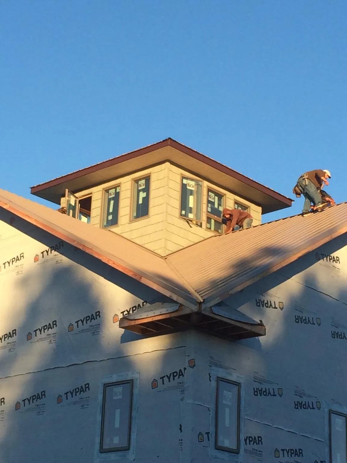 Roofers working around a rooftop cupola on a new metal roof at sunset — Roof Waterproofing in Cumberland City by Roofing Brothers